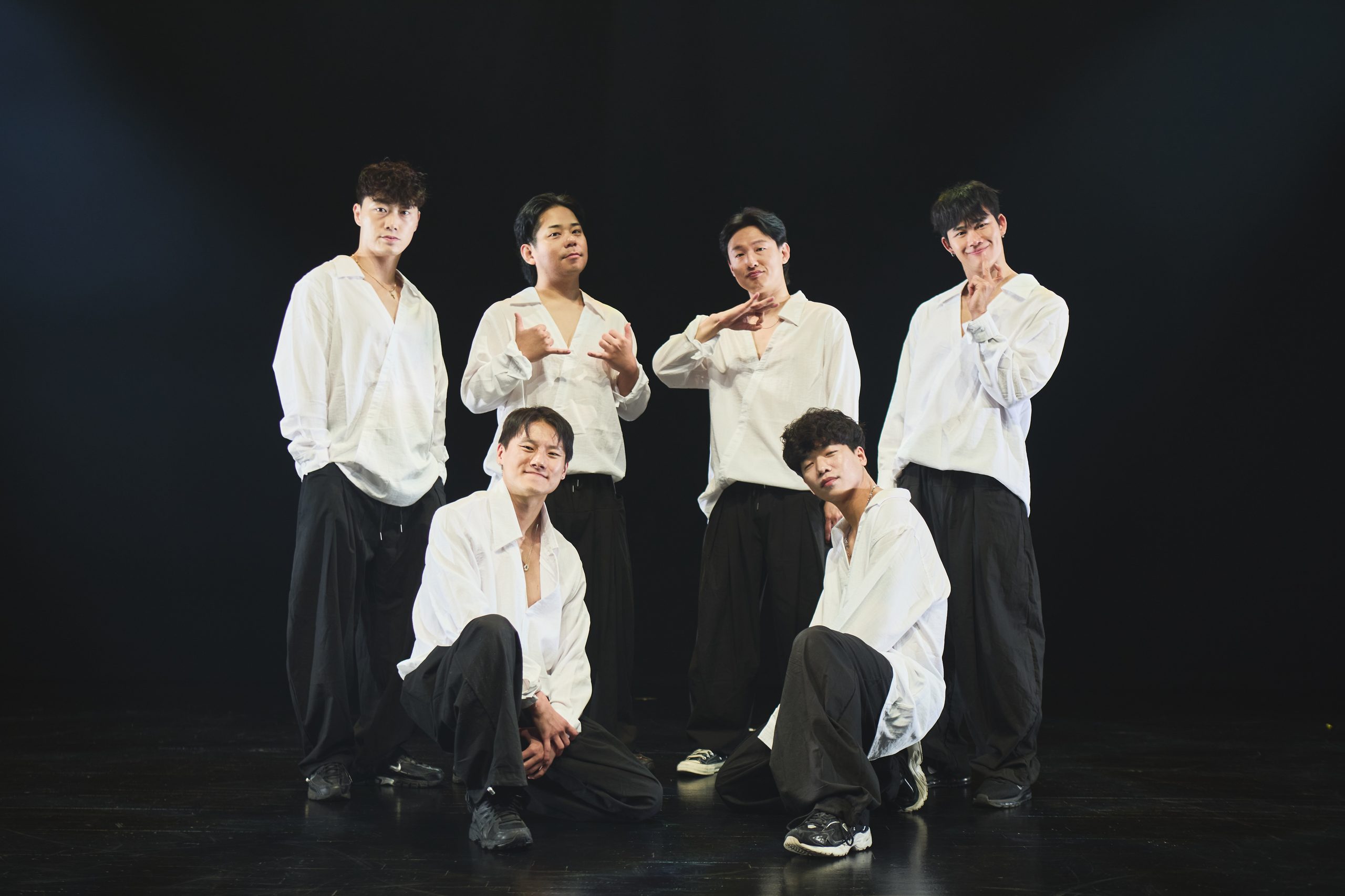 흰 셔츠와 검은 바지 차림의 나인티 단원 여섯 명이 무대 위에서 포즈를 취한 단체 사진
